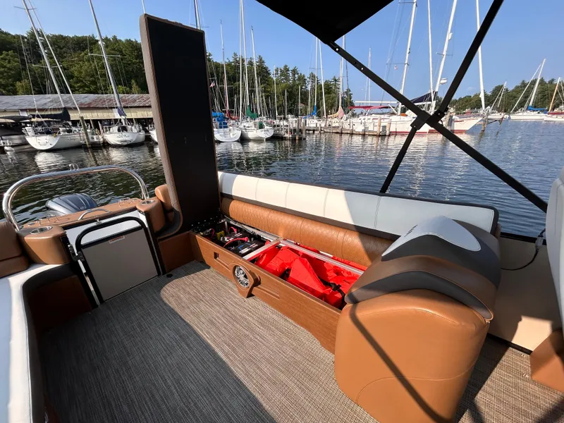 Slide: The Image of 2024 Avalon Catalina Quad Lounge boat interior at marina, showcasing seating and storage. - 12
