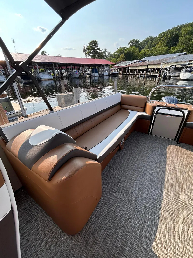 Slide: The Image of 2024 Avalon Catalina Quad Lounge boat interior with plush seating by a marina. - 15