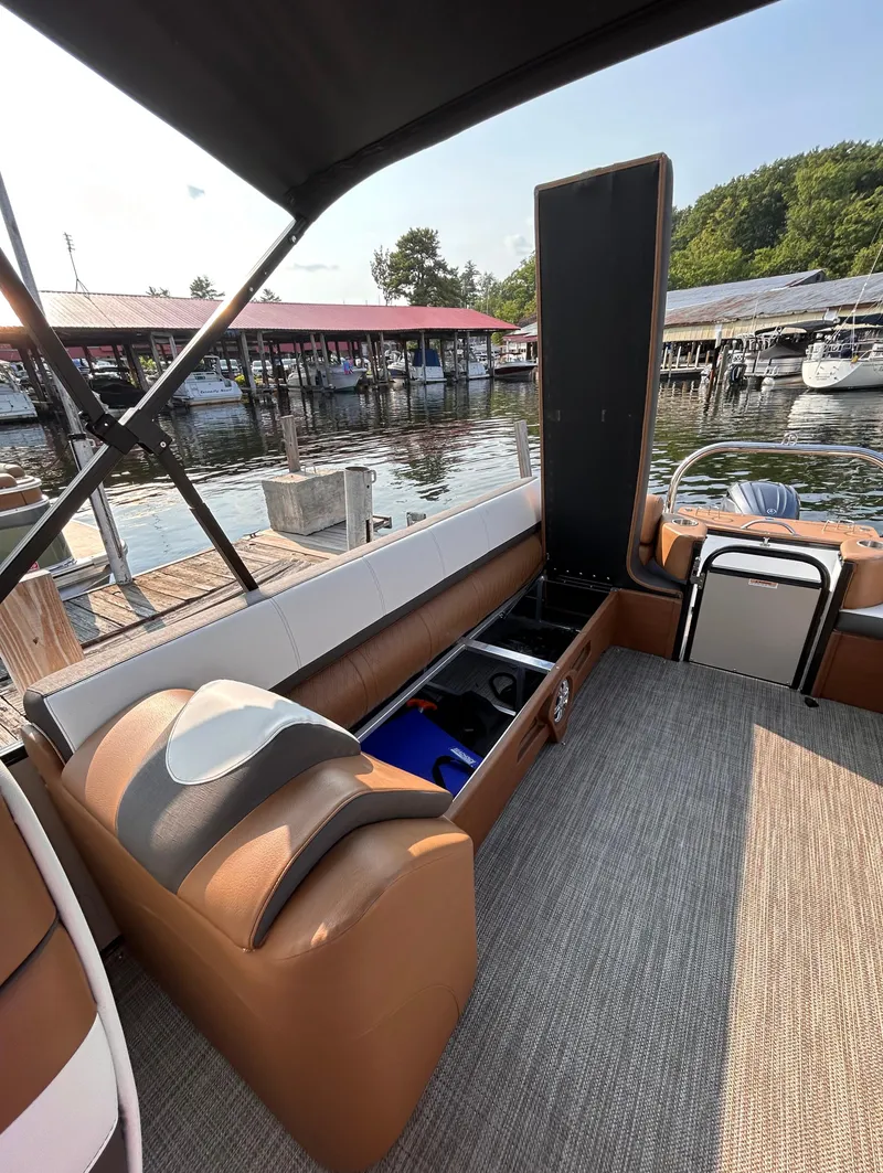 Slide: The Image of 2024 Avalon Catalina Quad Lounge boat interior with open storage, dockside view. - 16