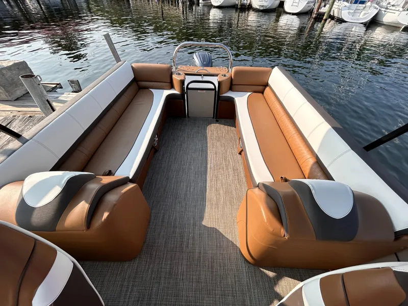 Slide: The Image of 2024 Avalon Catalina Quad Lounge 25' interior with brown and white seating, docked by the water. - 19