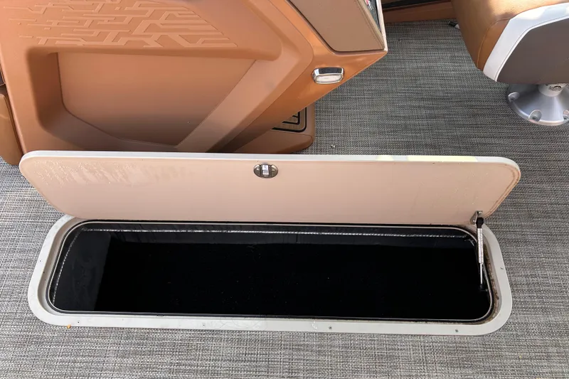 Slide: The Image of 2024 Avalon Catalina Quad Lounge storage compartment with open hatch on carpeted floor. - 26