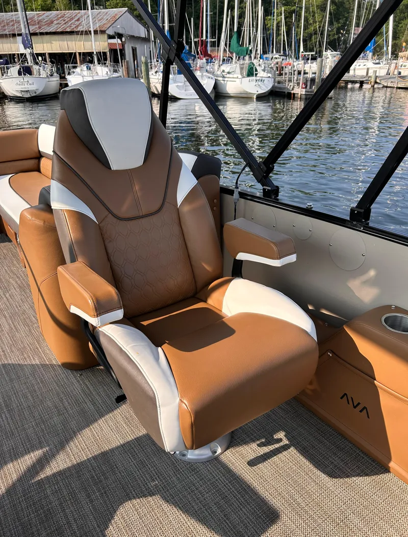 Slide: The Image of 2024 Avalon Catalina Quad Lounge boat seat with brown and white upholstery, docked near sailboats. - 27