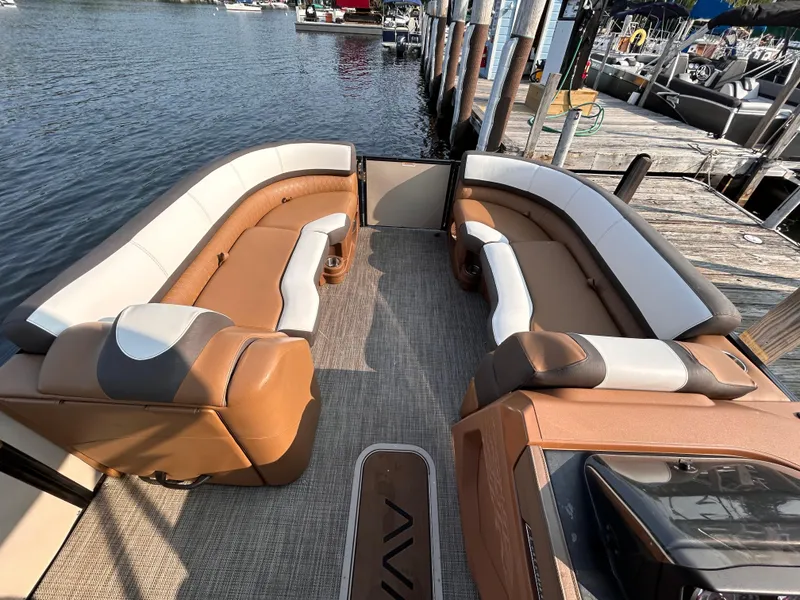 Slide: The Image of 2024 Avalon Catalina Quad Lounge 25' boat interior with tan and white seating at a dock. - 30