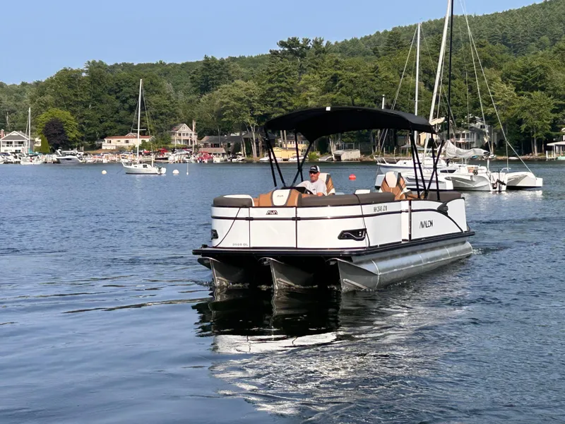 Slide: The Image of 2024 Avalon Catalina Quad Lounge 25' pontoon boat cruising on a scenic lake. - 5