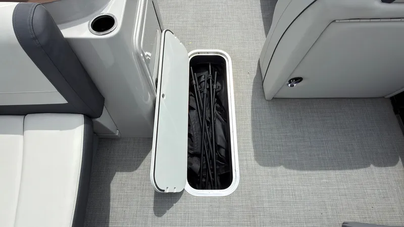 Slide: The Image of The image shows a storage compartment in the floor of a boat with gray carpeting. - 26