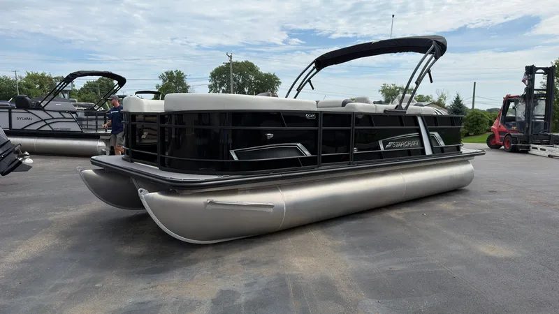 Slide: The Image of 2025 Starcraft EXS 3 FD TT pontoon boat with black hull and bimini top on a parking lot. - 6