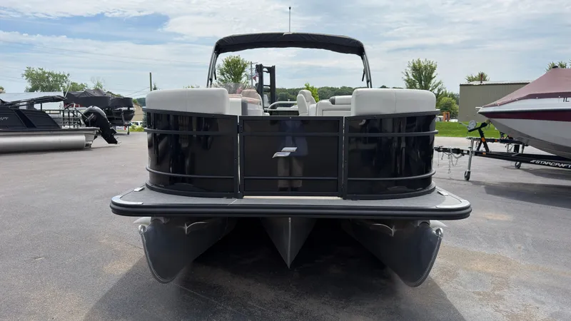 Slide: The Image of A 2025 Starcraft EXS 3 FD TT pontoon boat is parked. It features a black railing and white seats. - 8