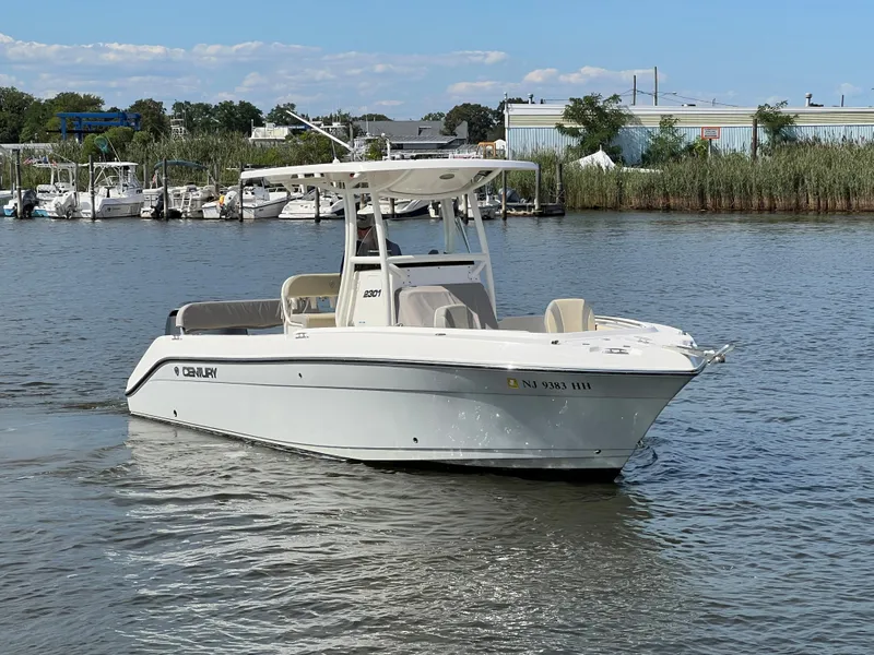 Slide: The Image of 2020 Century 2301 Center Console boat on calm water, surrounded by greenery and buildings. - 12