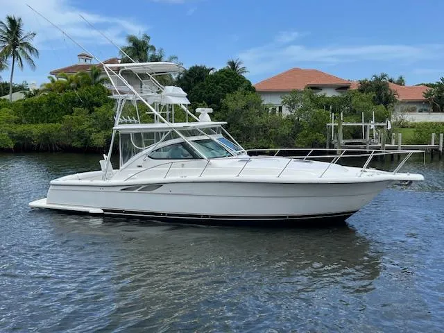 Slide: The Image of 2003 Tiara Yachts 3800 Open boat on calm water, surrounded by lush greenery. - 10