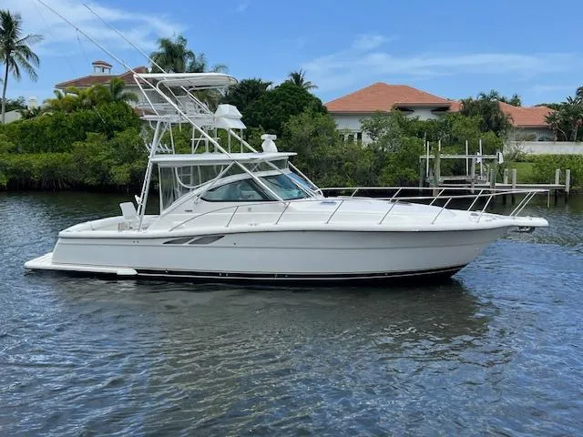 Slide: The Image of 2003 Tiara Yachts 3800 Open boat on calm water, surrounded by lush greenery. - 11