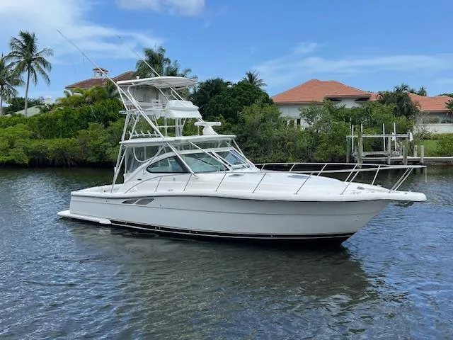 Slide: The Image of 2003 Tiara Yachts 3800 Open cruising on a calm waterway with lush greenery. - 9