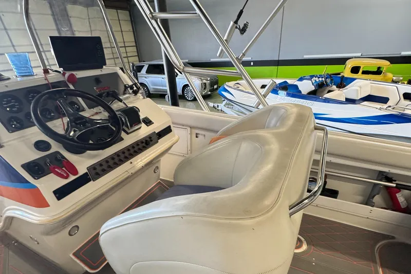 Slide: The Image of 1999 Wellcraft Scarab 302 boat interior with steering wheel and seating in a showroom. - 14