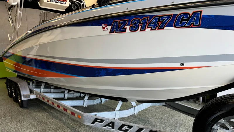 Slide: The Image of 1999 Wellcraft Scarab 302 boat on trailer, featuring vibrant blue and orange stripes. - 3