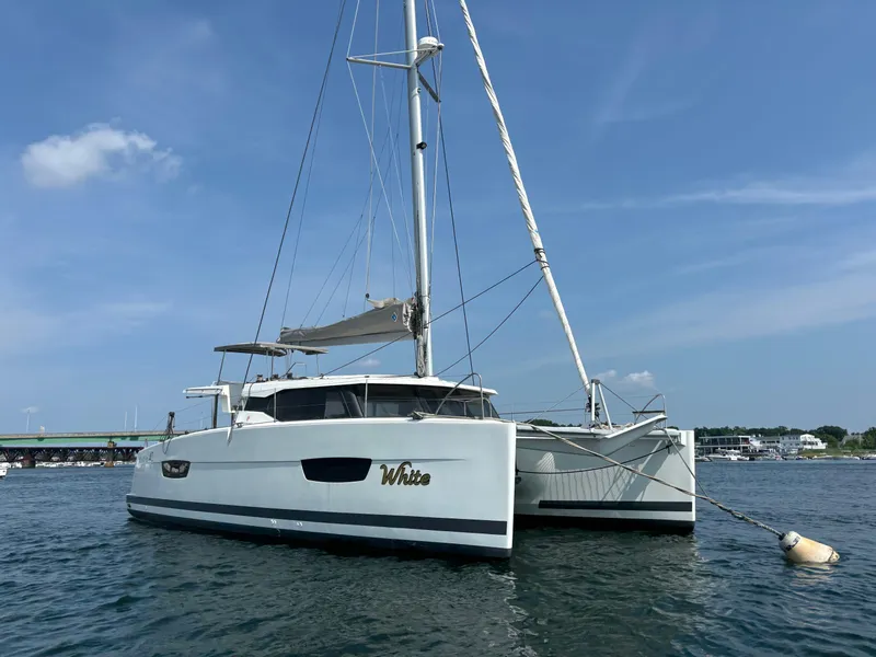 Slide: The Image of 2019 Fountaine Pajot Lucia 40 catamaran anchored on calm water under a clear blue sky. - 3