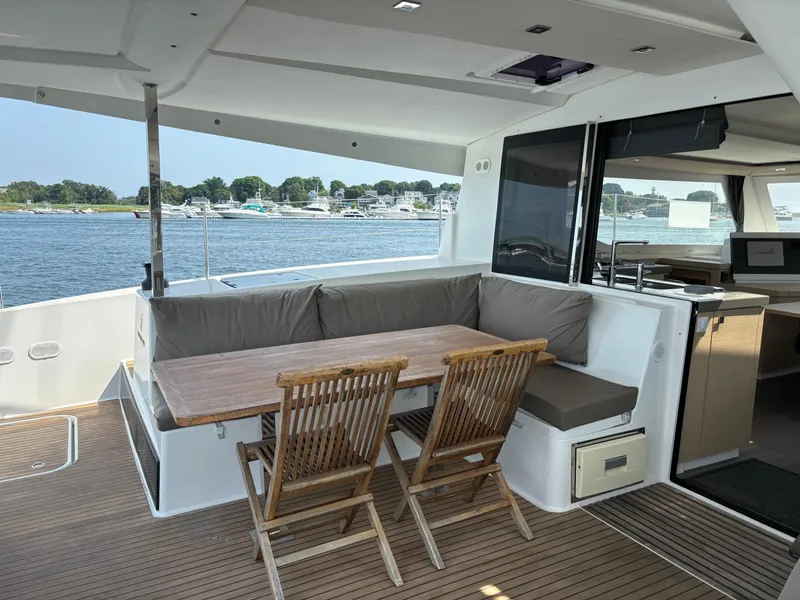 Slide: The Image of 2019 Fountaine Pajot Lucia 40 yacht, outdoor seating area with table, overlooking serene waters. - 36