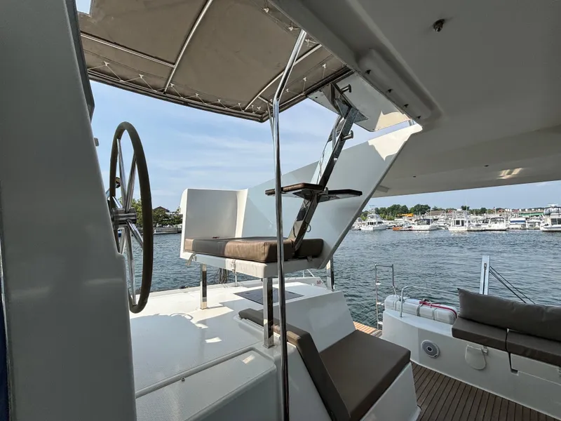 Slide: The Image of Fountaine Pajot Lucia 40 catamaran helm and seating area, 2019 model, docked by the water. - 39