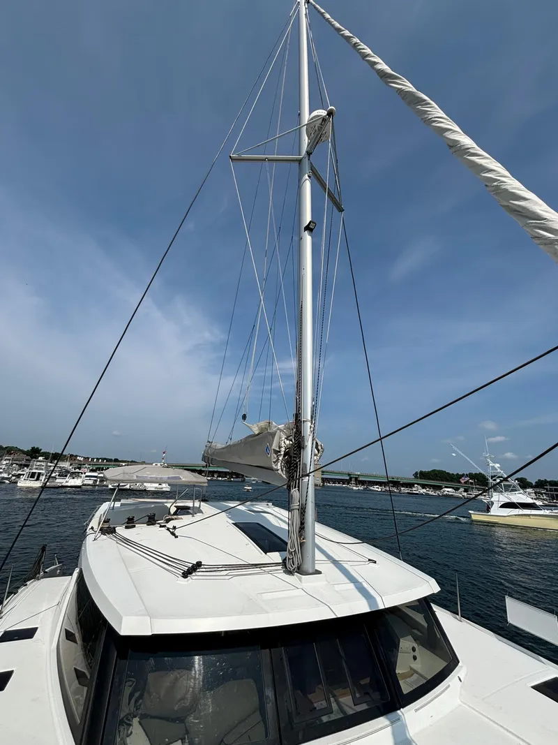 Slide: The Image of 2019 Fountaine Pajot Lucia 40 catamaran with mast, docked in a marina under clear skies. - 45
