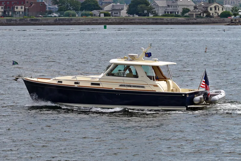 Slide: The Image of 2009 Sabre Hardtop Express boat cruising on a calm river with houses in the background. - 47