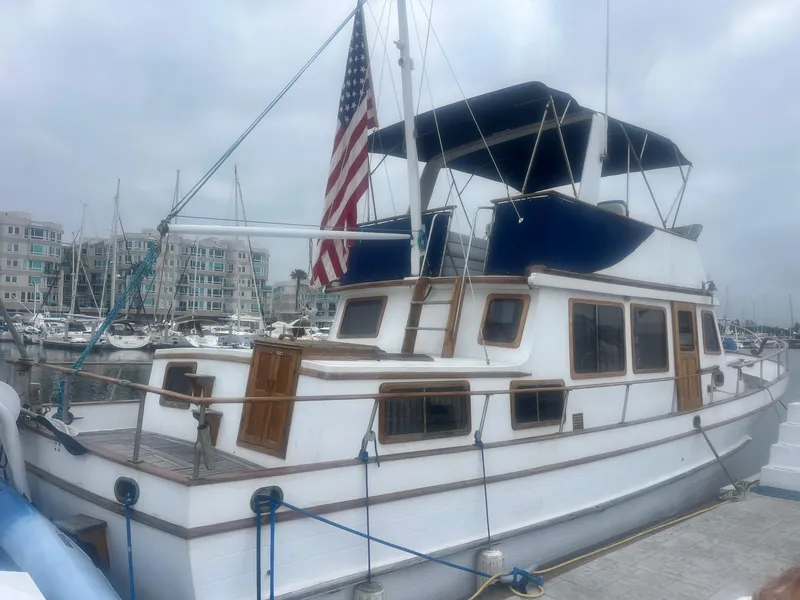 Slide: The Image of 1978 Marine Trader 44 Aft Cabin yacht docked at marina, featuring classic design and American flag. - 13