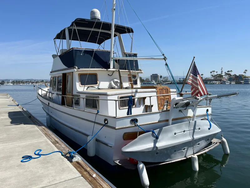 Slide: The Image of 1978 Marine Trader 44 Aft Cabin yacht docked at marina with American flag. - 4