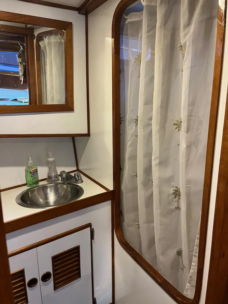 Slide: The Image of 1978 Marine Trader 44 Aft Cabin bathroom with sink and shower curtain. - 8