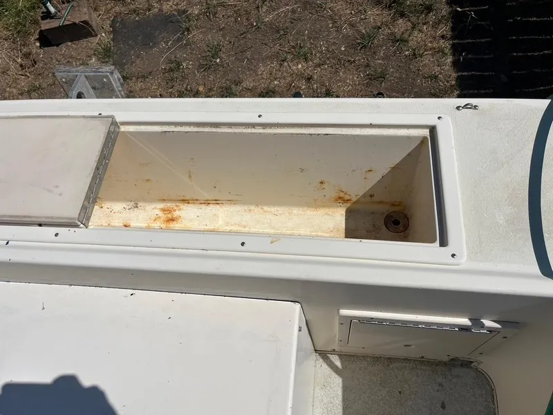 Slide: The Image of Open storage compartment on a 1994 Parker 2520 boat, showing interior wear and rust. - 19