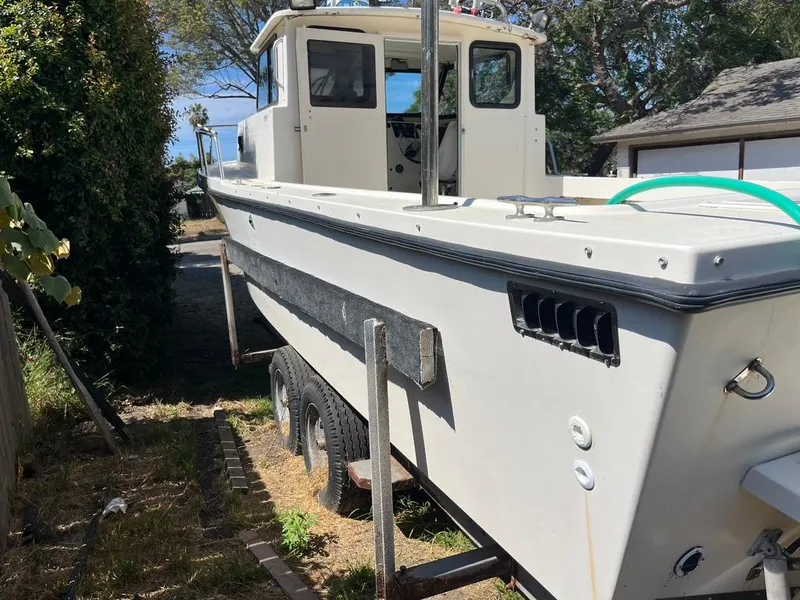 Slide: The Image of 1994 Parker 2520 boat on trailer, parked outdoors near trees and a building. - 4