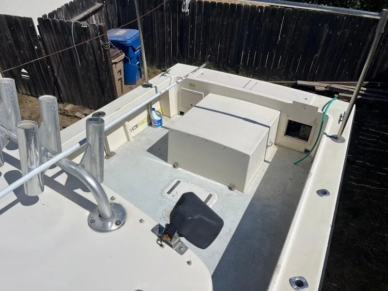 Slide: The Image of 1994 Parker 2520 boat deck with storage compartments and rod holders, in a fenced yard. - 5