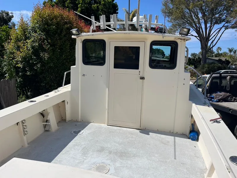 Slide: The Image of 1994 Parker 2520 boat with spacious deck and cabin, surrounded by trees. - 6