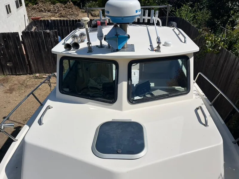 Slide: The Image of 1994 Parker 2520 boat cabin with radar and antennas, docked in a fenced yard. - 8