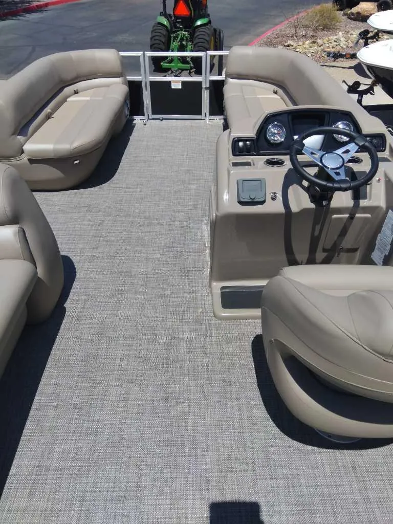Slide: The Image of 2024 Ranger Reata 200C pontoon boat interior with beige seating and steering console. - 4