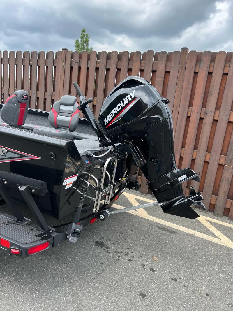 Slide: The Image of 2024 Ranger VS1665T boat with Mercury outboard motor, parked near wooden fence. - 2