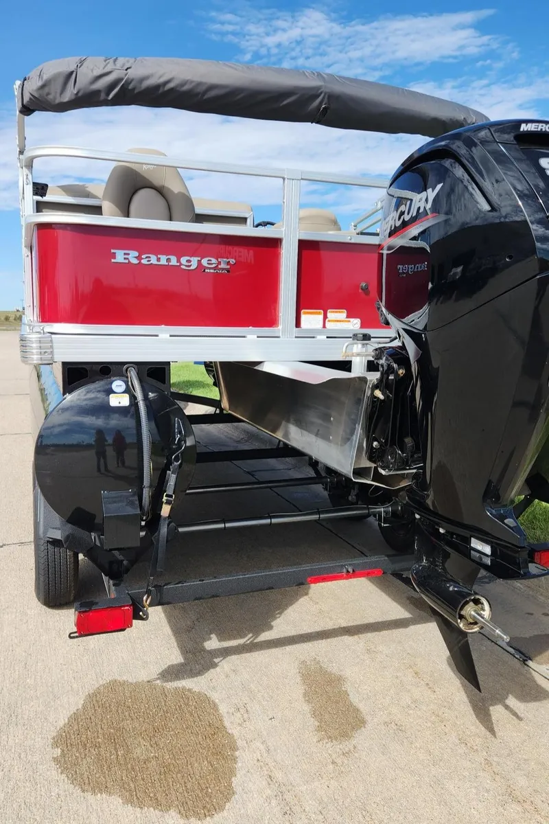 Slide: The Image of 2024 Ranger Reata 200F boat with Mercury engine, red exterior, parked on a trailer. - 2