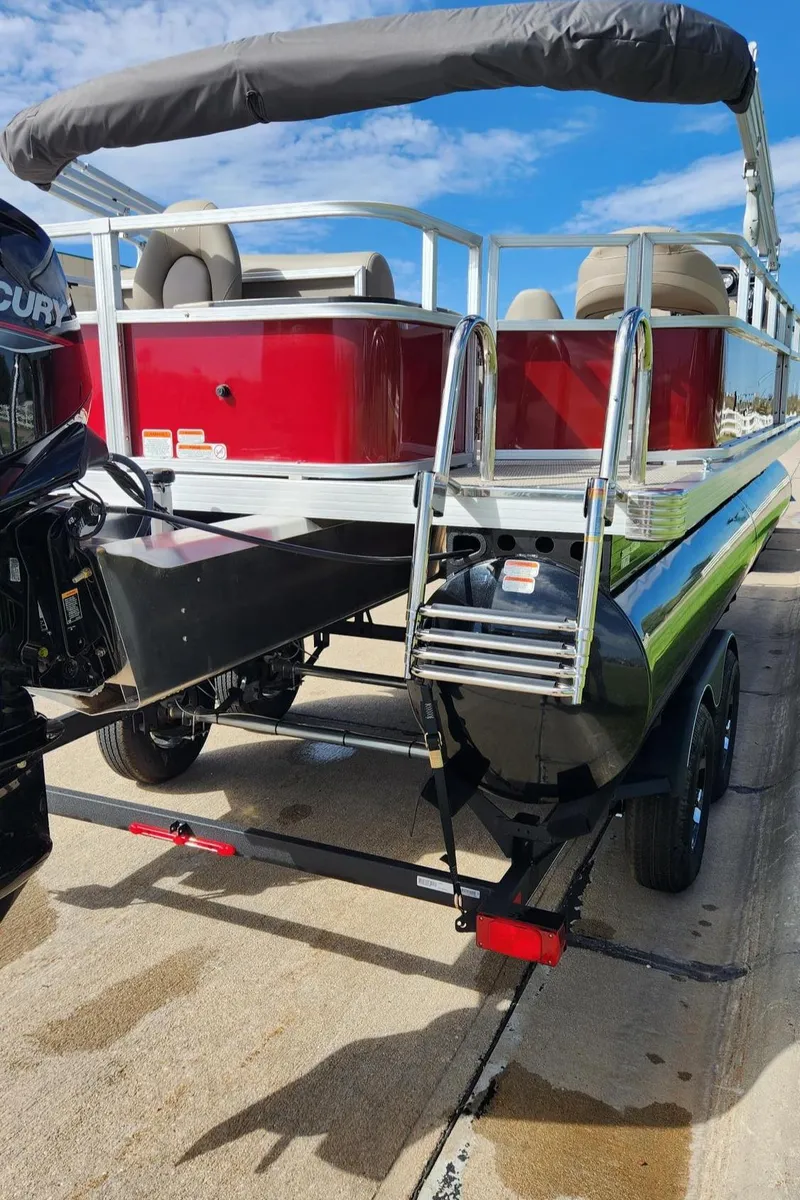Slide: The Image of 2024 Ranger Reata 200F pontoon boat with red exterior and canopy on a trailer. - 4