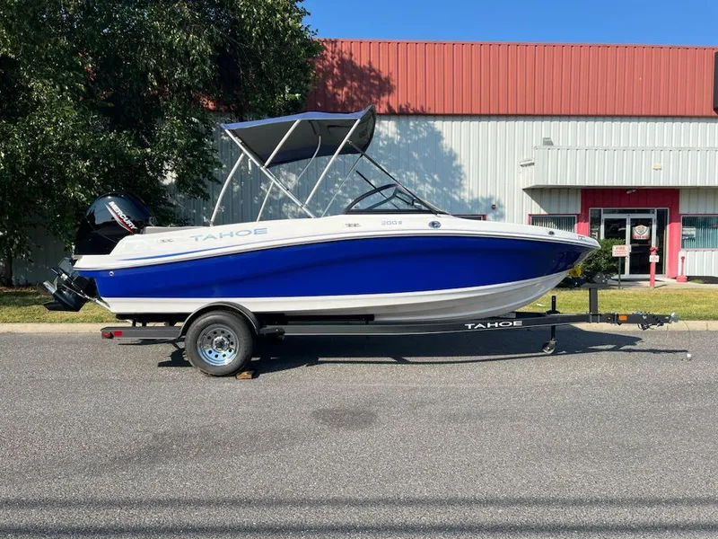 Slide: The Image of 2024 Tahoe 200 S boat with blue hull on trailer, parked outdoors. - 0