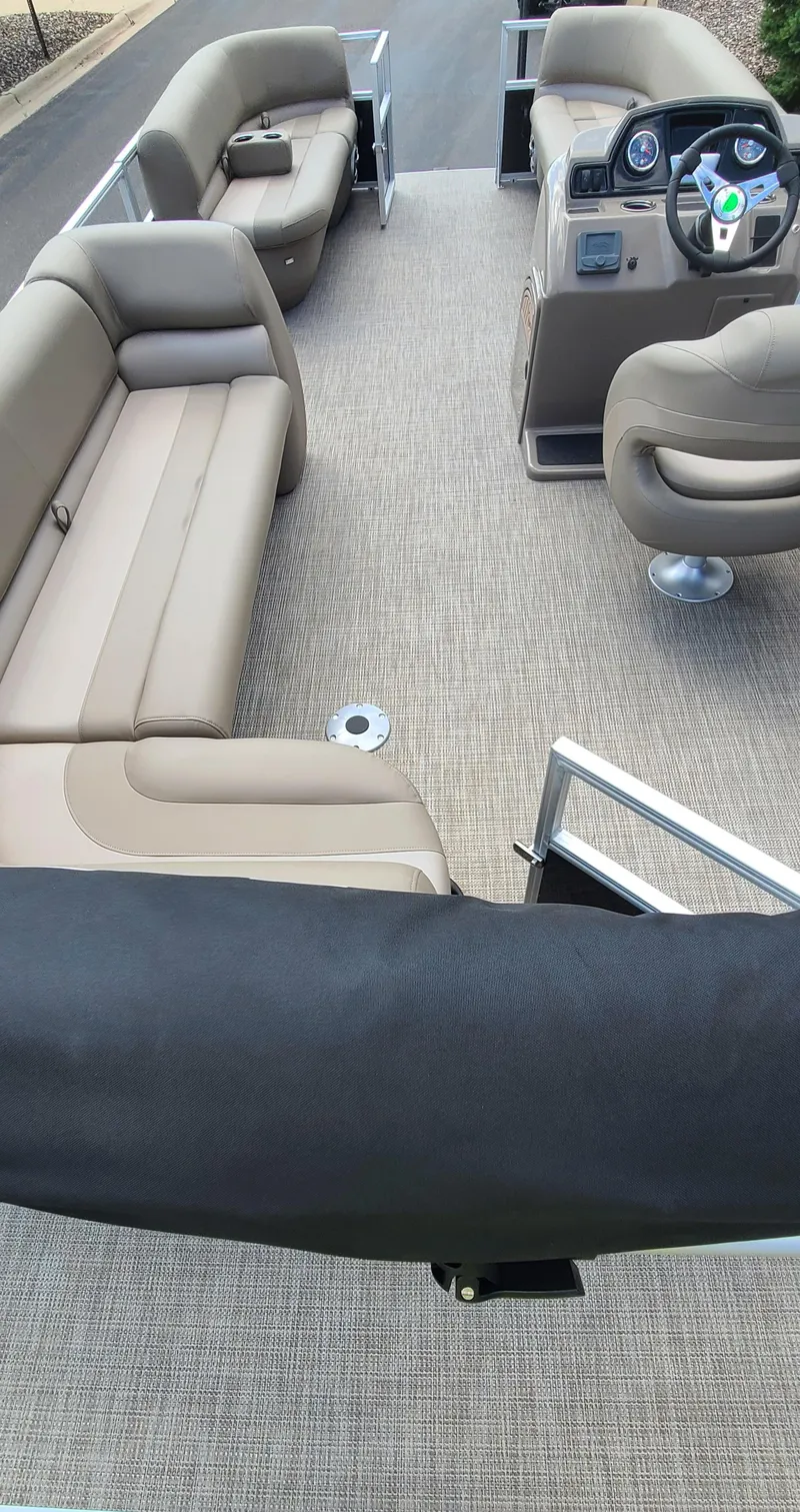 Slide: The Image of 2024 Ranger Reata 200C pontoon boat interior with beige seating and steering console. - 4