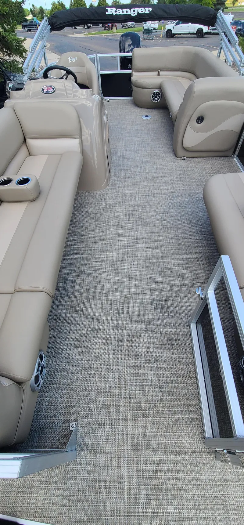 Slide: The Image of 2024 Ranger Reata 200C pontoon boat interior with beige seating and carpet flooring. - 5