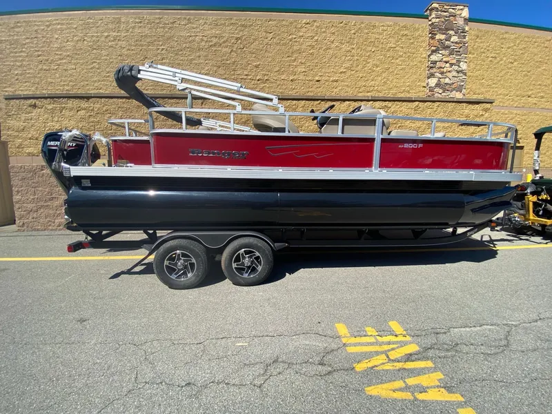 The Image of 2024 Ranger Reata 200F pontoon boat with red and black design on a trailer. - 0