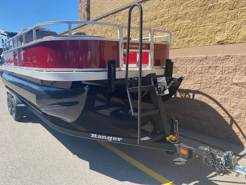 Slide: The Image of 2024 Ranger Reata 200F pontoon boat on trailer, red and black design, parked outdoors. - 2