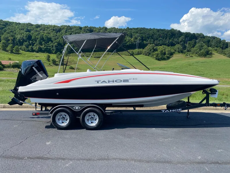 The Image of 2024 Tahoe 2150 boat on trailer, parked outdoors with scenic background. - 0