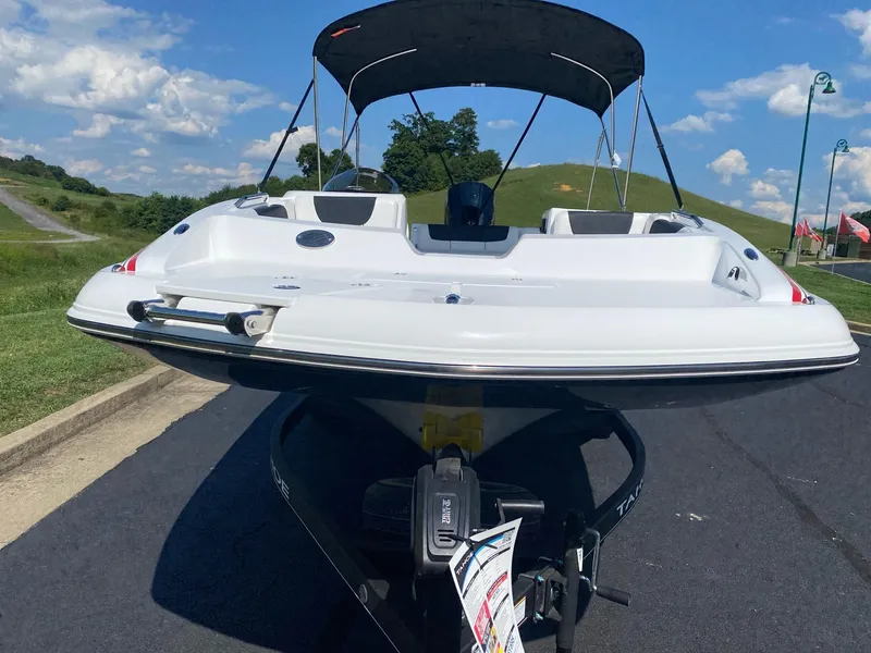 Slide: The Image of 2024 Tahoe 2150 boat with canopy on a sunny day, parked on a road. - 2