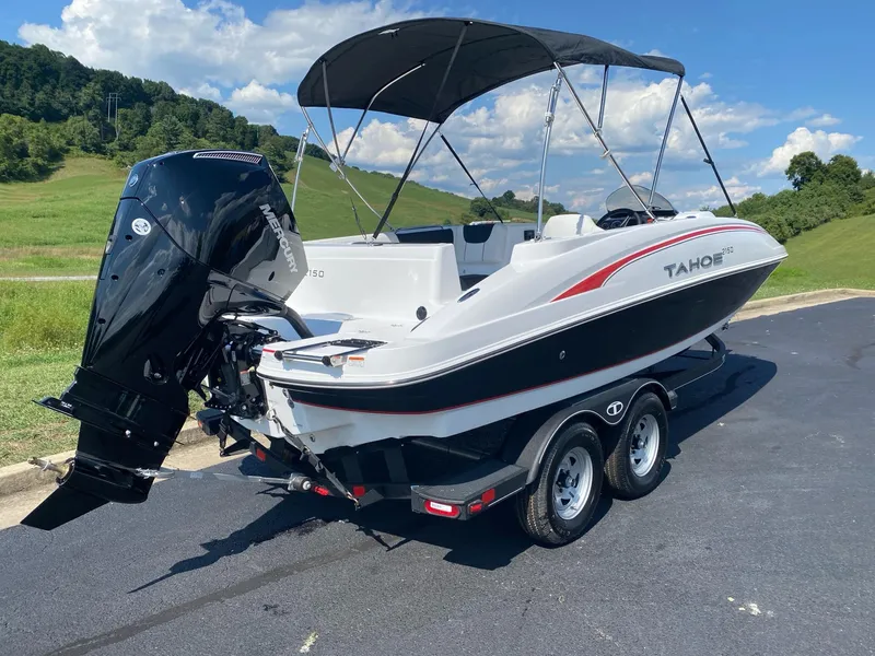 Slide: The Image of 2024 Tahoe 2150 boat with canopy on a trailer, parked on a sunny day. - 3