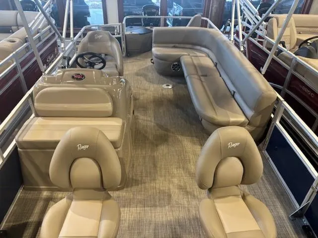 Slide: The Image of 2024 Ranger Reata 200F pontoon boat interior with beige seating and steering console. - 3