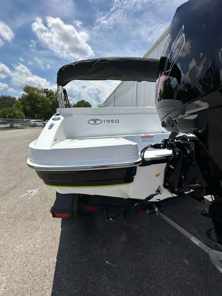 Slide: The Image of 2024 Tahoe 1950 boat, white exterior, parked outdoors under a partly cloudy sky. - 7