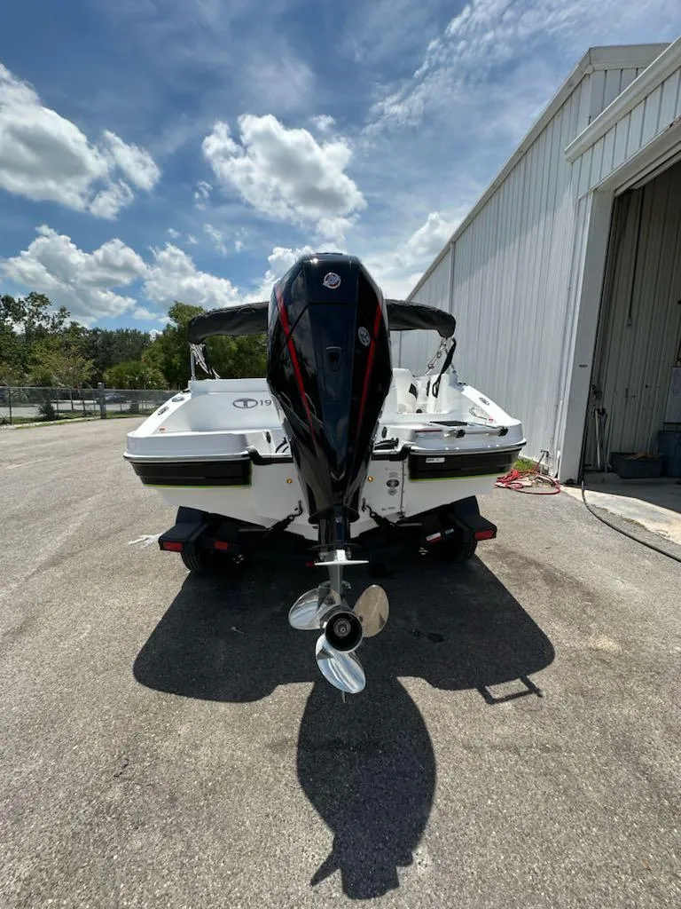 Slide: The Image of 2024 Tahoe 1950 boat with outboard motor, parked near a white building under a blue sky. - 8