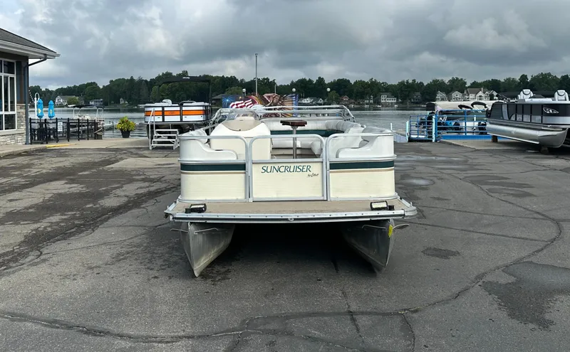 Slide: The Image of 1999 Suncruiser Trinidad 200 pontoon boat docked by a lakeside marina. - 2