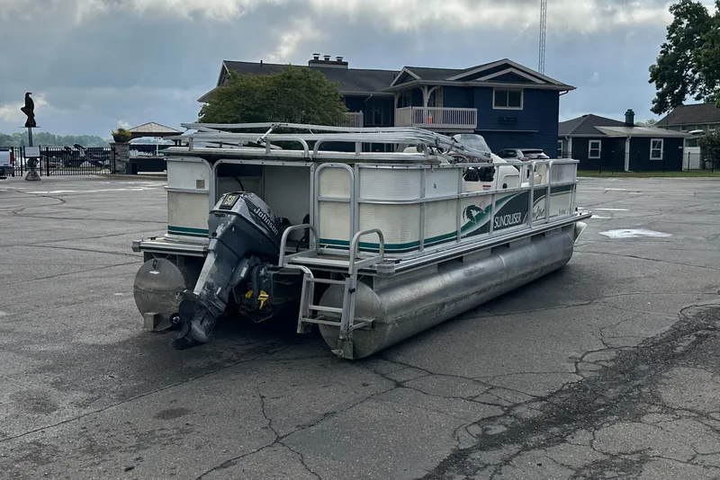 Slide: The Image of 1999 Suncruiser Trinidad 200 pontoon boat parked on a paved surface near buildings. - 3