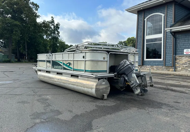 Slide: The Image of 1999 Suncruiser Trinidad 200 pontoon boat parked near a building, featuring an outboard motor. - 4