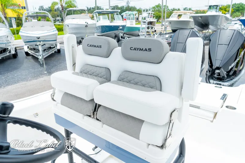 Slide: The Image of 2025 Caymas 281 HB boat seats, white and gray, in a showroom with other boats. - 13