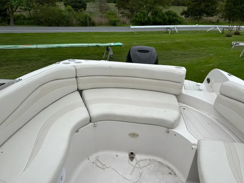 Slide: The Image of 2004 Starcraft Aurora 2410 boat interior with white cushioned seating on grassy area. - 5